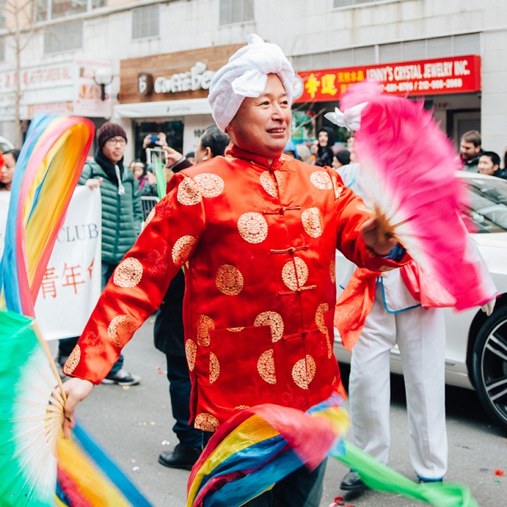 Man dancing with rainbow coloured ribbons as part of New York's Chinese New Year street party.