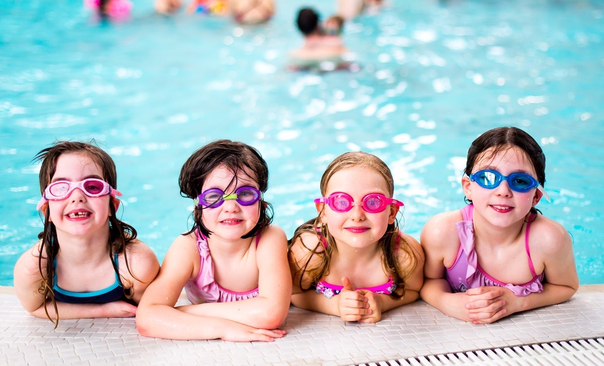 Girls with their goggles on having a break from all the fun at the edge of the pool.