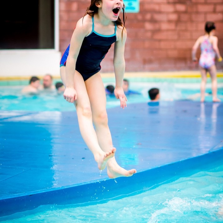 Girl jumping into the outdoor pool.